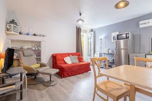 Un espace de vie moderne comprenant un canapé, une table à manger et un coin cuisine avec un réfrigérateur et un four à micro-ondes.