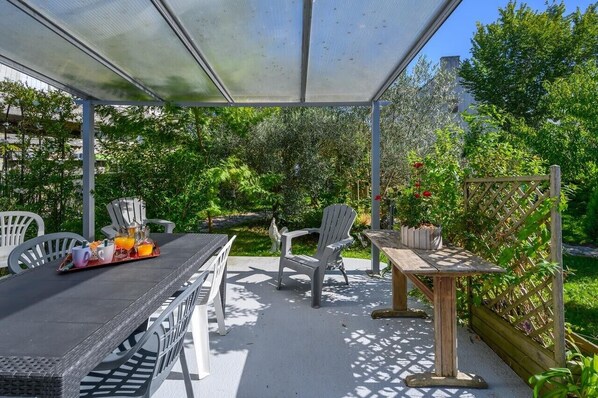 An outdoor patio with a table, chairs, and a wooden table.