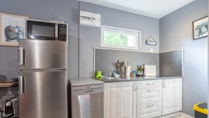 A modern kitchen with stainless steel appliances, a window, and a countertop with various items.