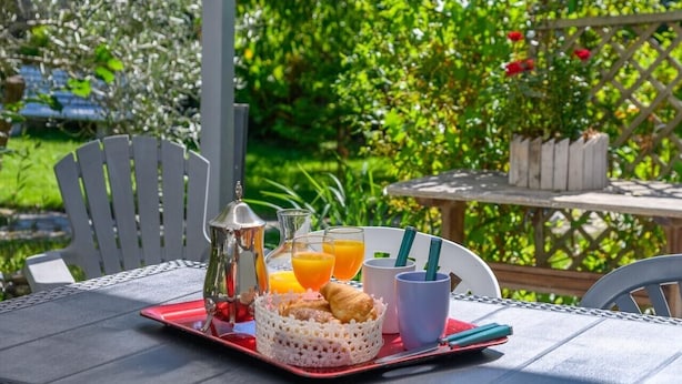 A breakfast setup with a tray, a basket, a pitcher, glasses, and a croissant.
