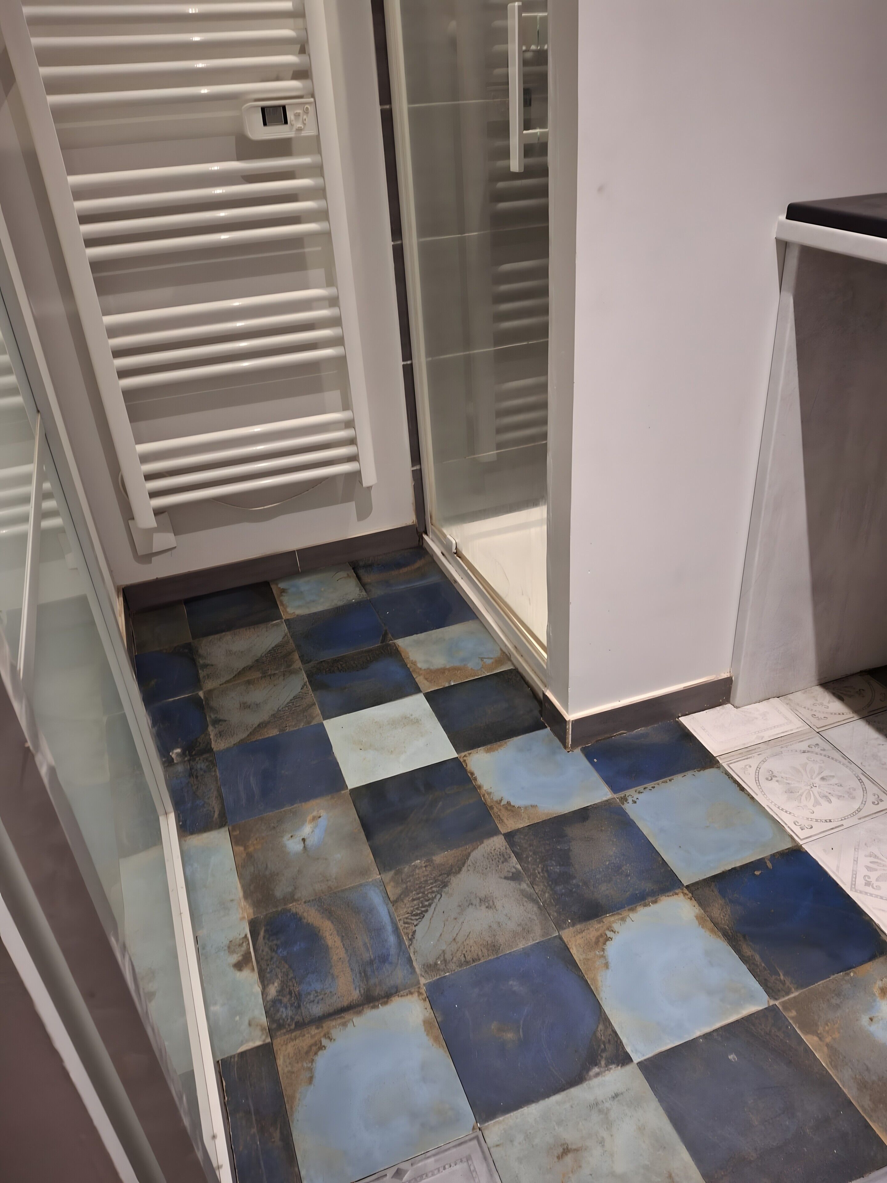 Um quarto com piso de azulejos, porta de vidro e parede branca.