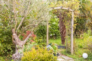 A garden with a wooden arbor, various plants, and a pathway. - Studio L'Eclose - Ty Du with Private Terrace, Shared Garden & Wi-Fi – Cyclist Friendly, Near GR34 (Guilvinec)