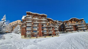 A multi-story wooden building with balconies, surrounded by snow-covered trees.