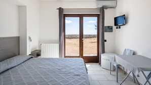 A bedroom with a bed, a desk, a television, and a view of the outdoors. - Holiday Home 'Ami' with Sea View, Private Terrace and Shared Garden (Arzana)
