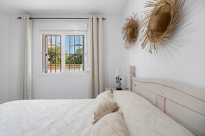 Une chambre à coucher avec un lit, des rideaux, une fenêtre et un élément de décoration fixé au mur.