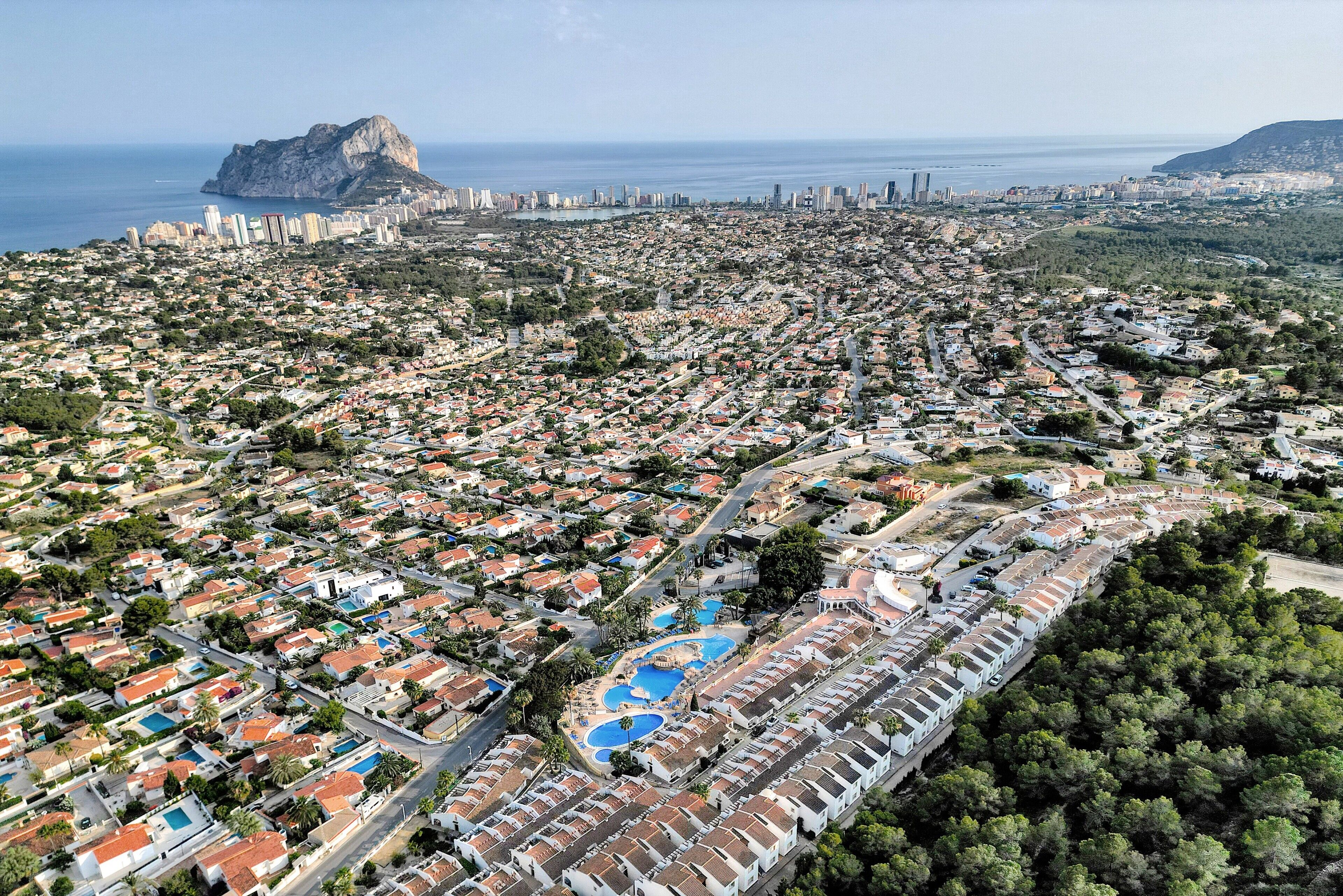 Ein Luftbild einer Küstenstadt mit dichter Wohnbebauung, einem markanten Berg und einer weiten Wasserfläche.
