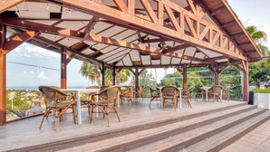 A covered outdoor seating area with wooden flooring and wicker chairs, overlooking a scenic view. - Holiday Apartment "Clementina Imperial Park" with Sea View, Shared Pool & Wi-Fi (Calp)