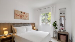 A bedroom with a bed, bedside lamps, a nightstand, a wall-mounted mirror, and a window with curtains. - Holiday Apartment "Clementina Imperial Park" with Sea View, Shared Pool & Wi-Fi (Calp)