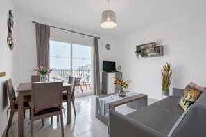 Un soggiorno moderno con angolo pranzo, divano, televisore e balcone con vista.