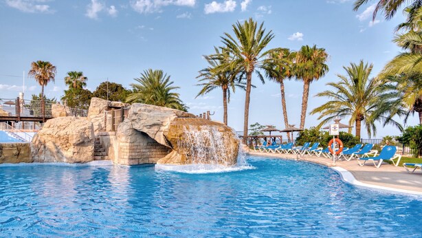 A pool with a waterfall feature, palm trees, and lounge chairs. - Holiday Apartment "Clementina Imperial Park" with Sea View, Shared Pool & Wi-Fi (Calp)