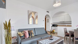 A modern living room with a grey sofa, a coffee table, and a dining area with chairs and a table. - Holiday Apartment "Clementina Imperial Park" with Sea View, Shared Pool & Wi-Fi (Calp)