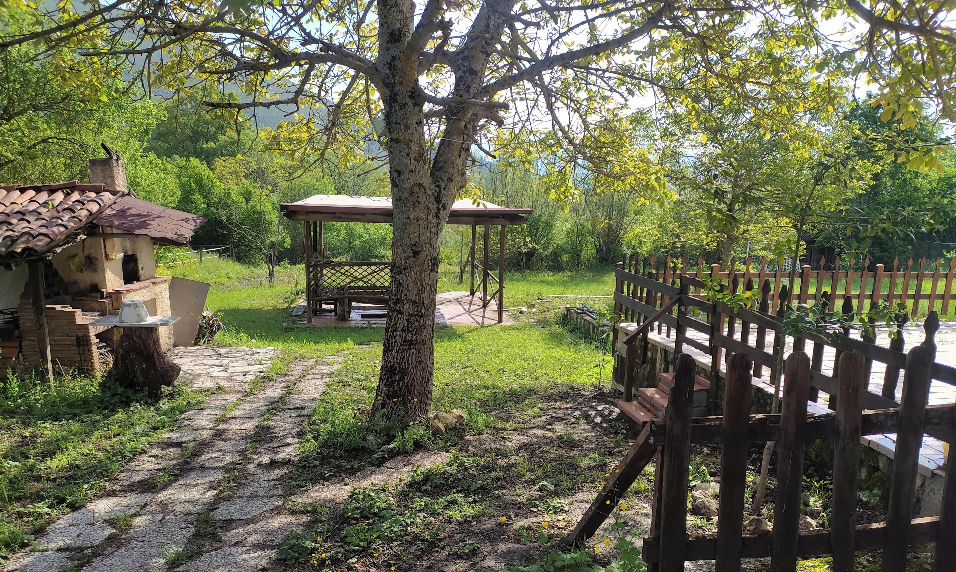 Ein rustikaler Außenbereich mit einem Pavillon, einer Ziegelstruktur und einem Holzzaun.