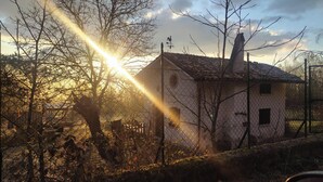 Une maison avec un toit en pente, une cheminée et une cour clôturée.