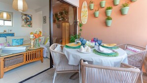 A dining area with wicker chairs, a round table, and a white tablecloth.