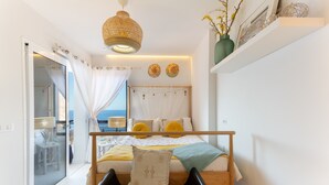 A bedroom with a bed, a chair, a balcony with a view, and a hanging light fixture.