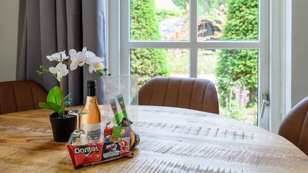 Ett matbord med en orkidé i en kruka, en ölflaska, några snacks och ett glas vatten.