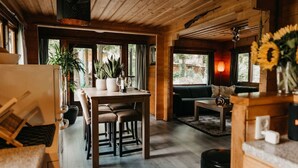 A cozy cabin interior with a wooden dining table, chairs, a sofa, and a fireplace. - Cozy and romantic forest house at Veluwe (Putten)