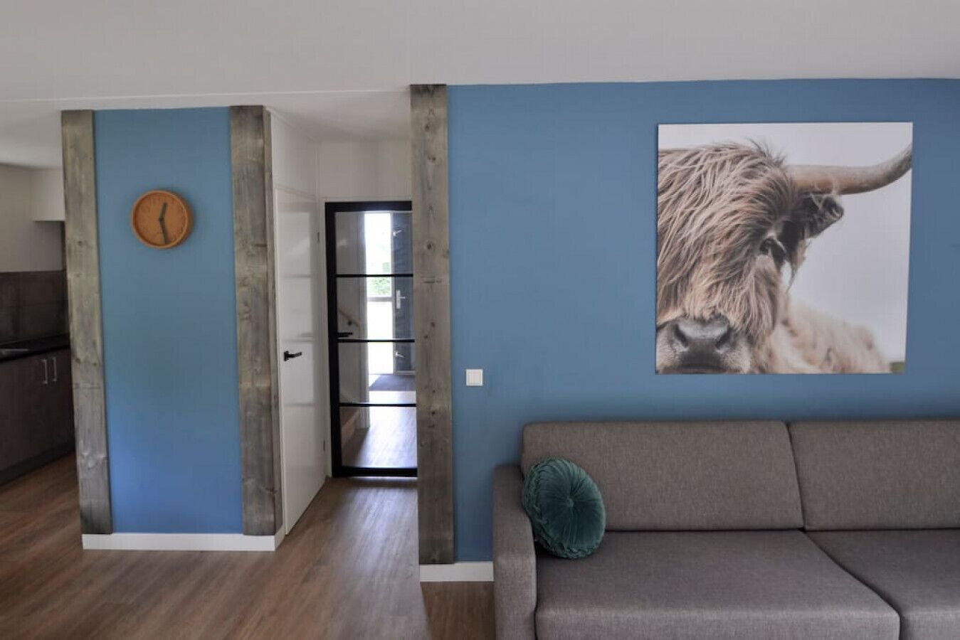 Un espacio de estar moderno con una pared azul de acento, un estampado animal grande y una puerta de madera.