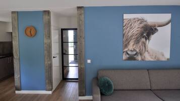 Un espacio de estar moderno con una pared azul de acento, un estampado animal grande y una puerta de madera.