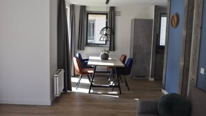 A modern dining area with a wooden table, chairs, and a vase of flowers. - Comfortable wellness house, everything new, located by the lake. (Ewijk)