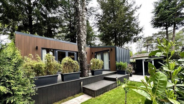 A modern house with a wooden deck, a small garden, and a shed. - VHNT76 · FIKA Luxury holiday home for 4 people at Veluwe (Hoenderloo)