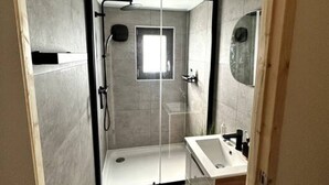 Une salle de bain moderne avec une douche à parois de verre, un lavabo et un miroir.
