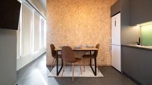 Uma cozinha moderna com mesa de jantar posta para quatro pessoas, forno embutido e janela que oferece luz natural.