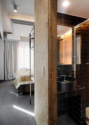 Una habitación de hotel moderna con una litera, un espejo grande y un baño con azulejos negros.