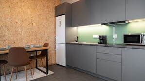 Uma cozinha moderna com armários cinza, uma máquina de café preta e um micro-ondas.