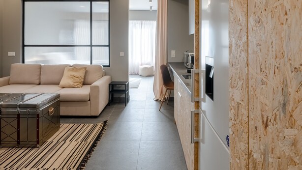 A modern living room with a sofa, a coffee table, and a kitchen area with a microwave. - Superior Mονόχωρο Διαμέρισμα, Psiri Vibes (Athens)