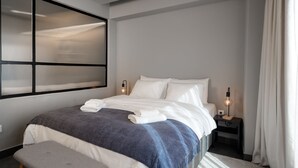 A modern hotel room with a large bed, a bench, a nightstand, and a wall-mounted light fixture. - Superior Mονόχωρο Διαμέρισμα, Psiri Vibes (Athens)