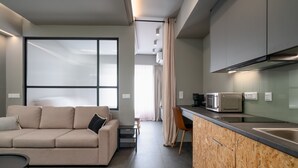 A modern apartment with a sofa, a dining area, and a kitchenette. - Superior Mονόχωρο Διαμέρισμα, Psiri Vibes (Athens)