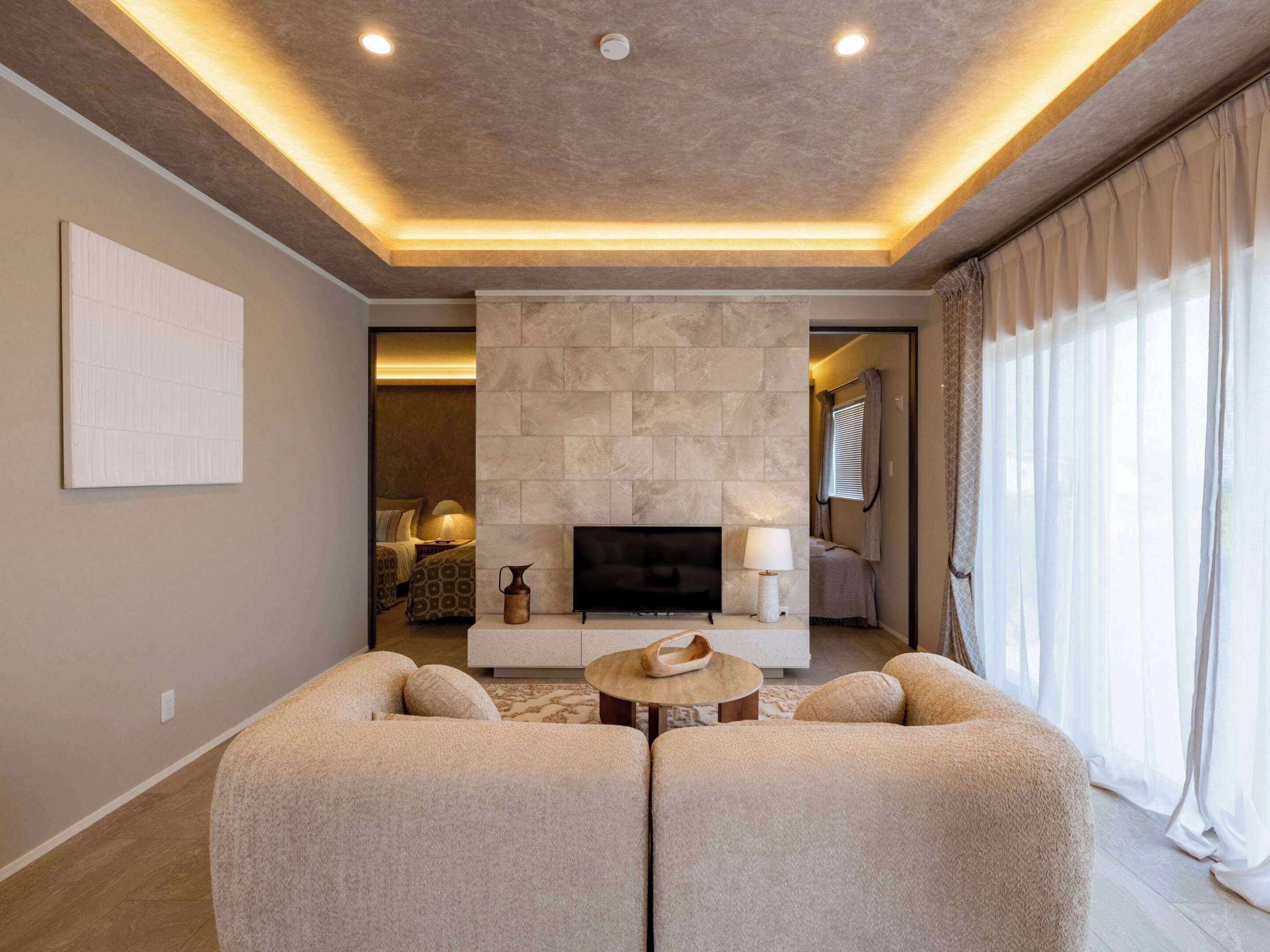 Un salon moderne avec un mur en pierre, un téléviseur à écran plat et un canapé.
