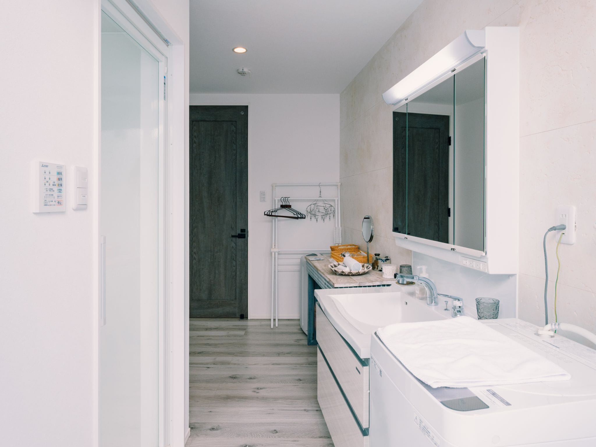 A modern bathroom with a double sink, a large mirror, and a wooden door.