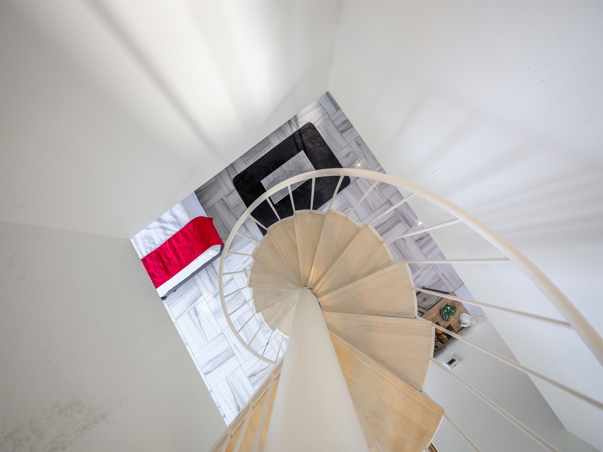 A spiral staircase in a room with a bed and a window.