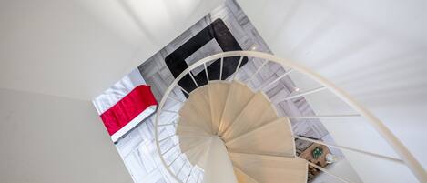 A spiral staircase in a room with a bed and a window.