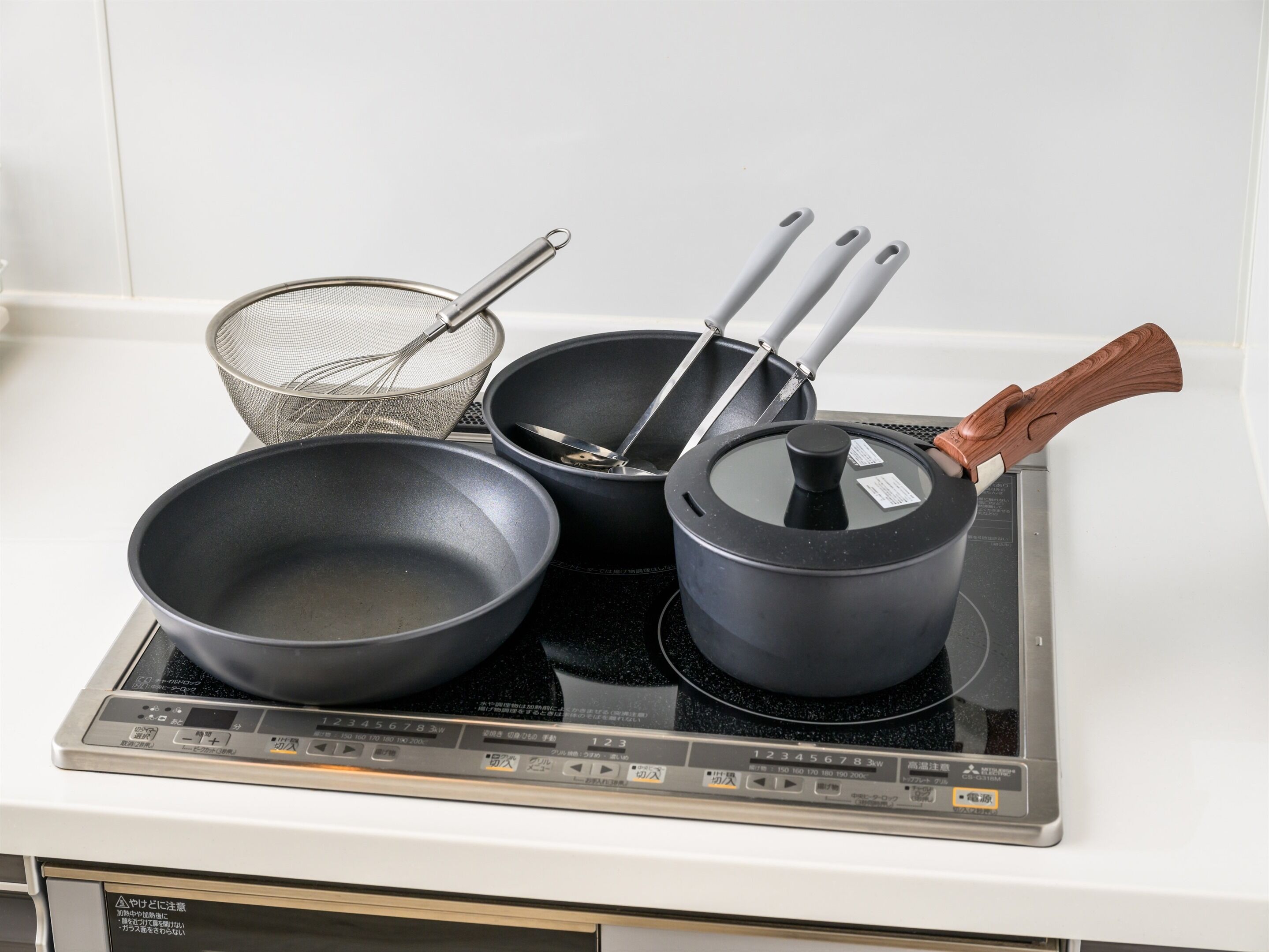 Una cocina con estufa, sartén, olla y colador.