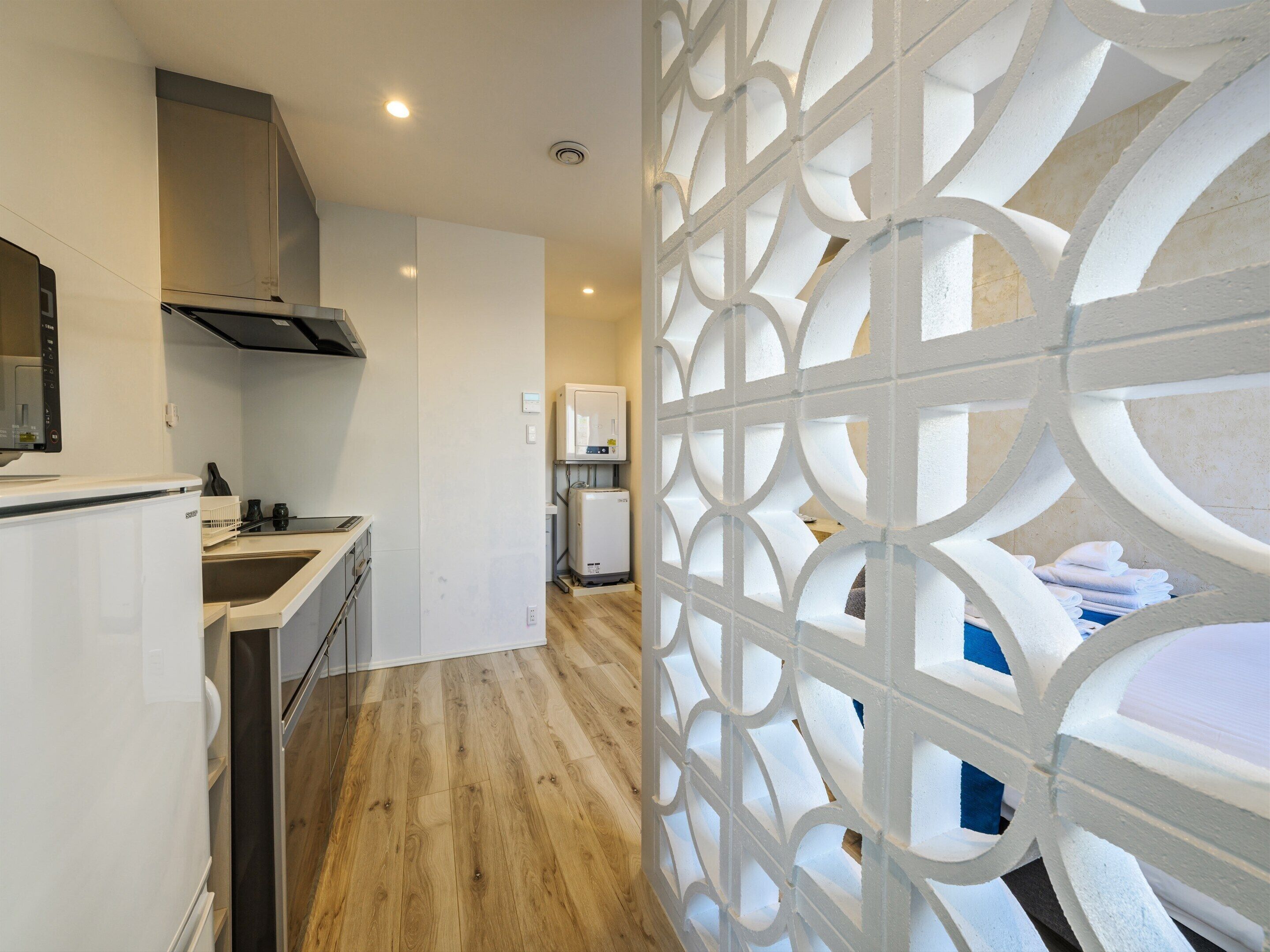 A modern kitchen with a built-in oven and a microwave, a wooden floor, and a decorative white partition.