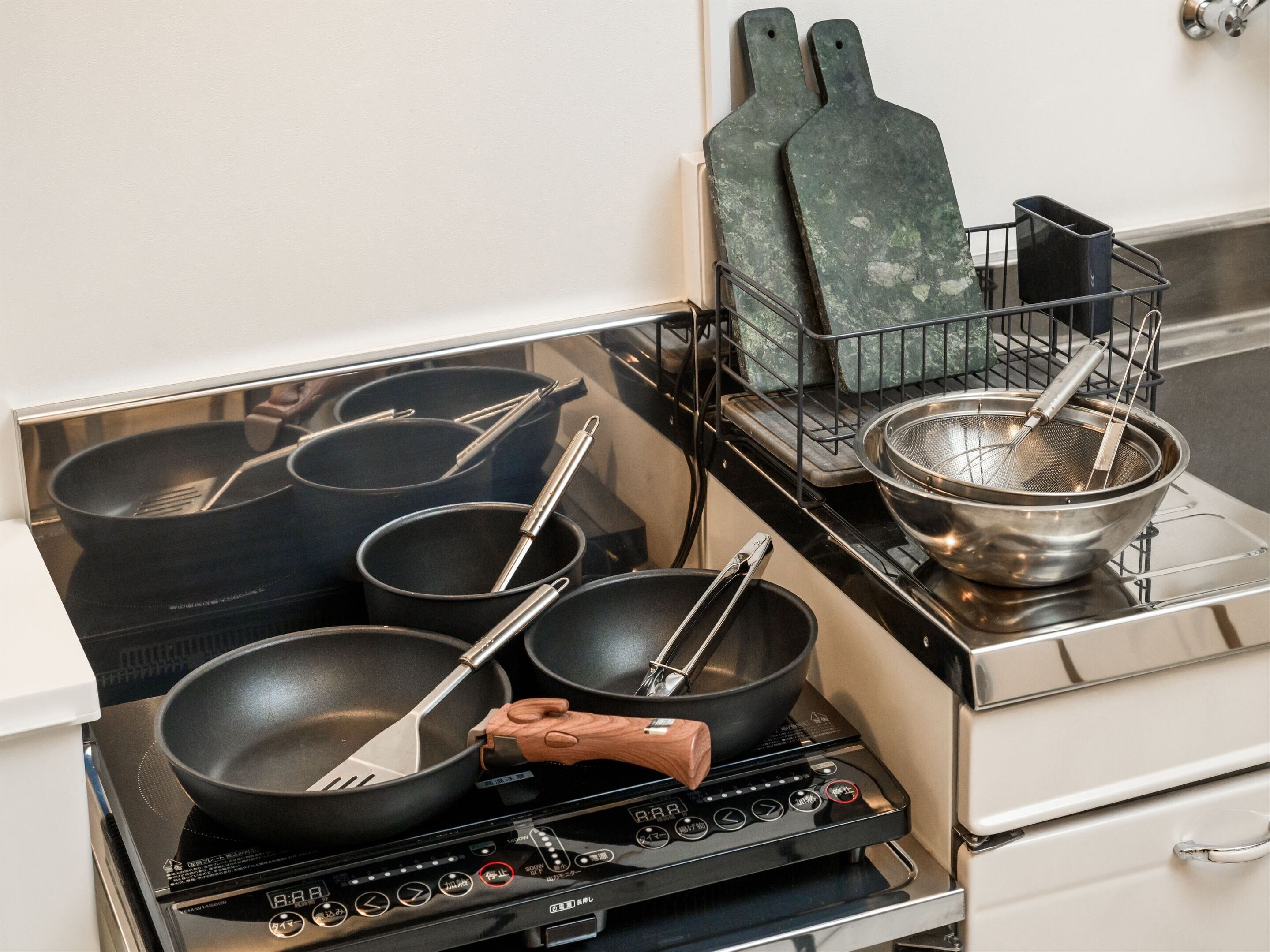 A kitchen with a stove, pots, pans, and a strainer.