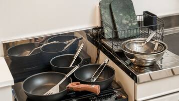 A kitchen with a stove, pots, pans, and a strainer.