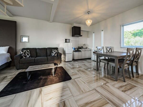 A modern living room with a sofa, coffee table, and dining area. - abundance okinawa & Kourijima Sauna resort (Nakijin)
