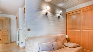 Une pièce avec un canapé beige, un tapis rouge et une armoire en bois.