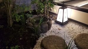 A garden with a stone water feature, pebbles, and plants. - Kyo no yado BOTAN (Kyoto)