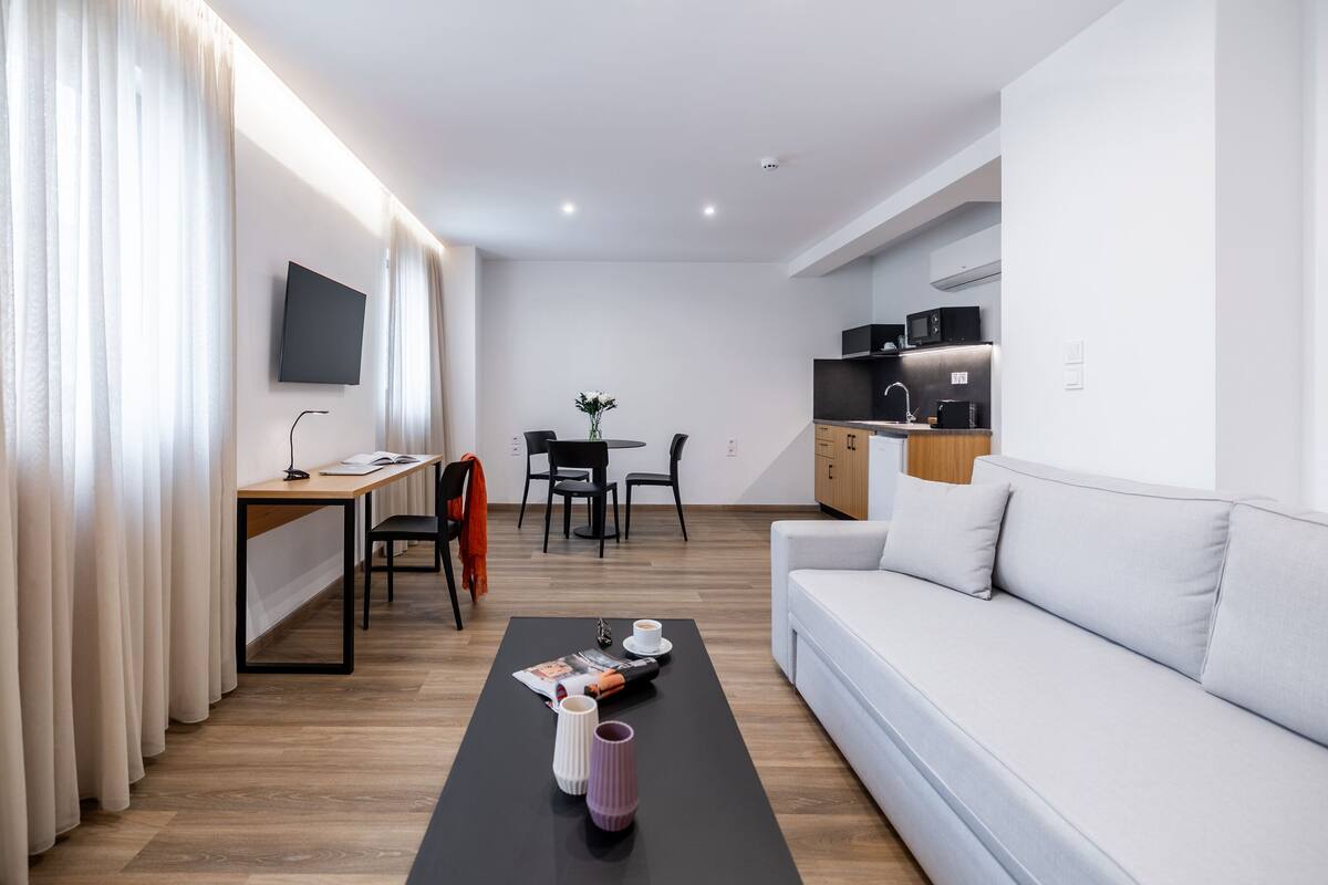 Uma sala de estar moderna com um sofá, uma mesa de centro e um espaço de jantar com uma mesa e cadeiras.