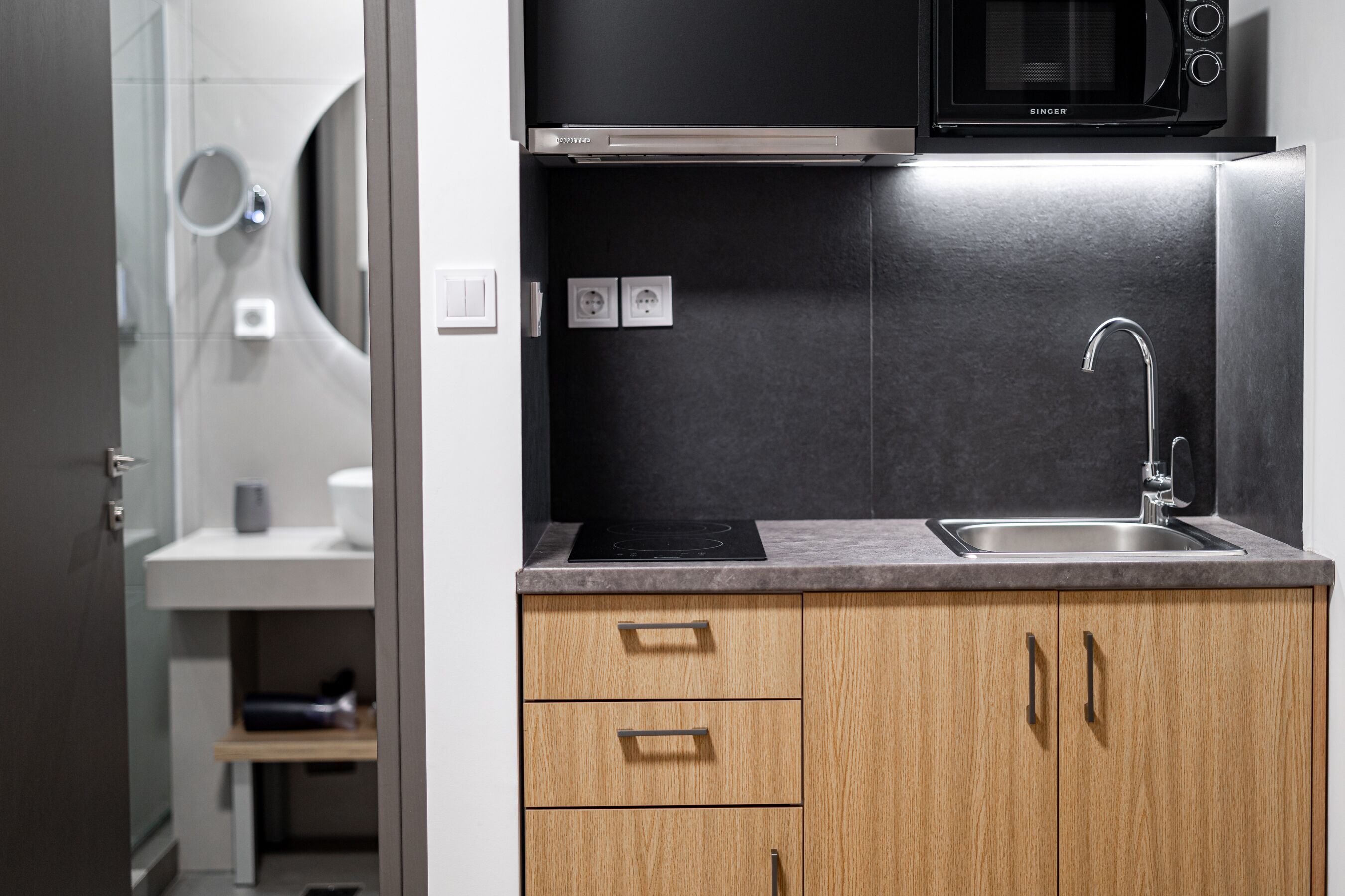 A modern kitchen with a built-in microwave, stainless steel sink, and wooden cabinets.