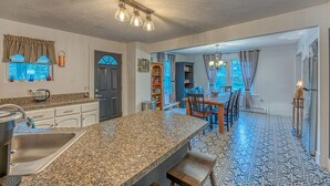A kitchen with granite countertops, a built-in sink, and a dining area with a table and chairs. - Riverfront House w/ Rooftop Deck! Dog Friendly! (Woodstock)