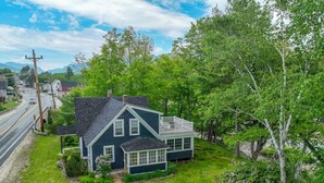 A two-story house with a dark blue exterior, a front porch, and a visible garage. - Riverfront House w/ Rooftop Deck! Dog Friendly! (Woodstock)