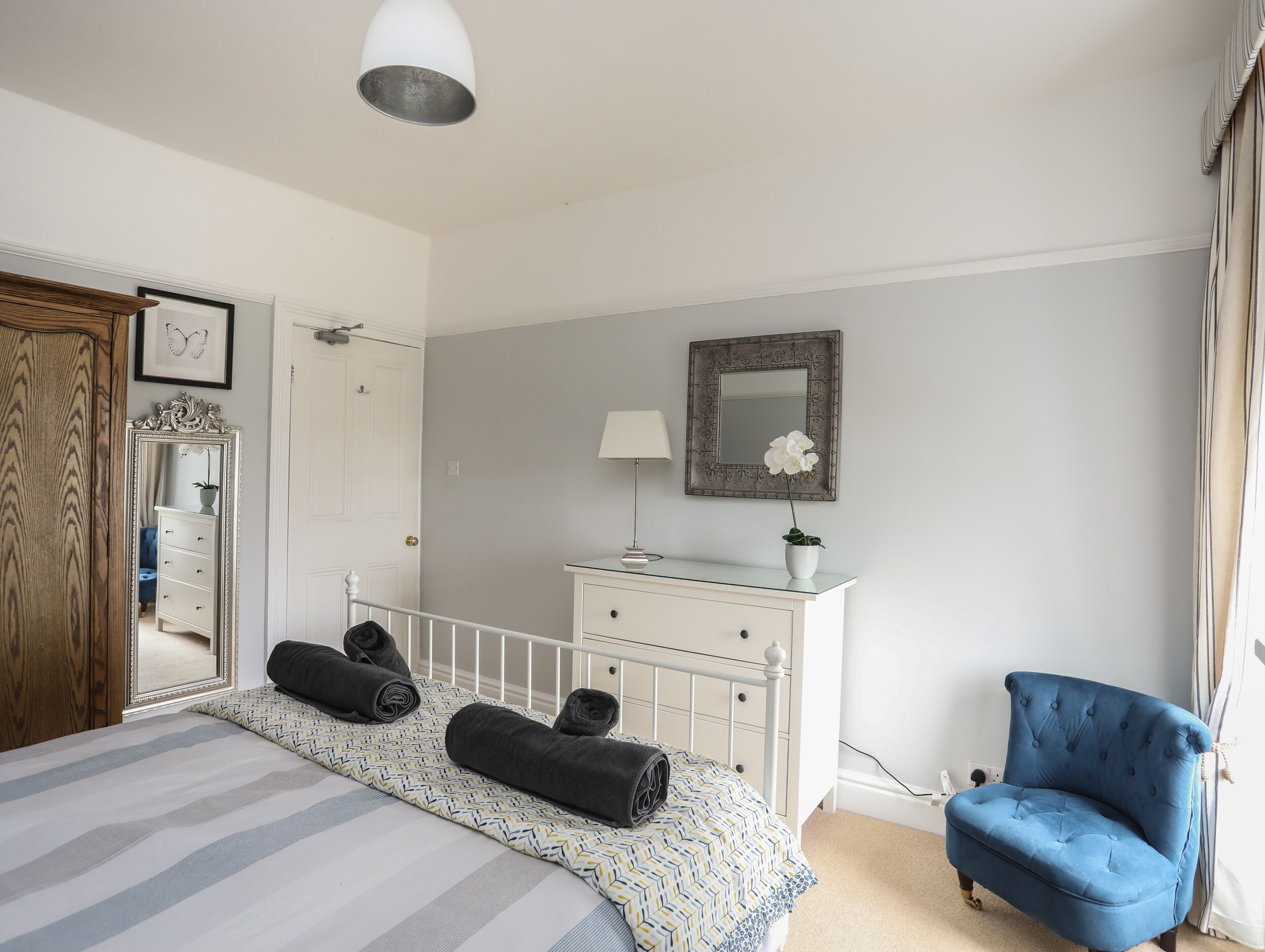 Un dormitorio con cama, cómoda, silla y espejo.