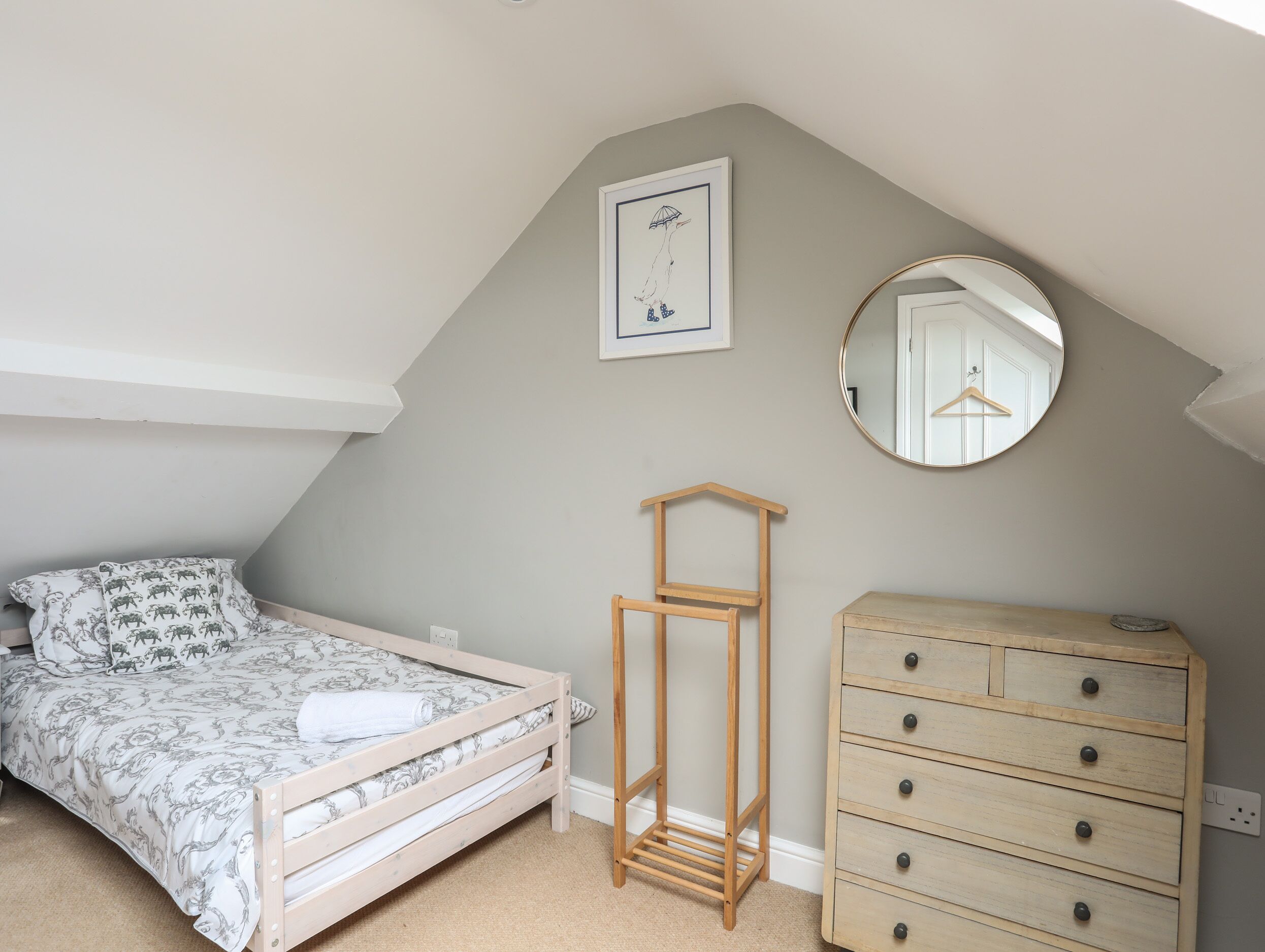 A bedroom with a bed, a dresser, a mirror, and a framed picture on the wall.