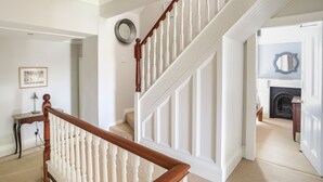 Un escalier avec des balustrades blanches et une main courante en bois menant à un palier.